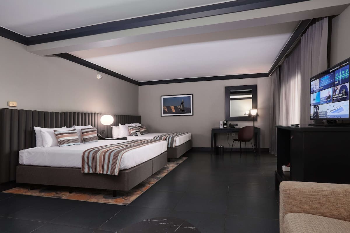 Una camera d'hotel moderna con un letto grande, una scrivania, una sedia e un televisore.