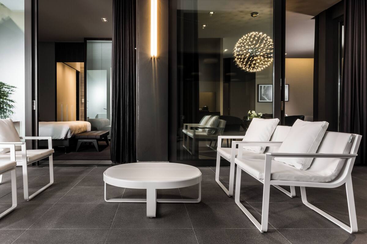 A modern living room with a white sofa set, a round coffee table, and a glass partition.