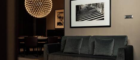 A modern living room with a dark sofa, a framed black and white photograph, and a unique spherical light fixture.