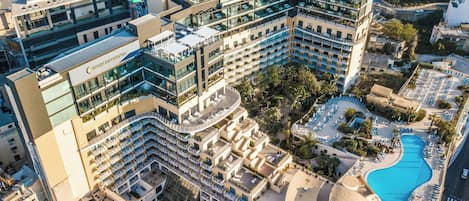 A multi-story hotel with a rooftop pool, outdoor seating, and a landscaped courtyard.