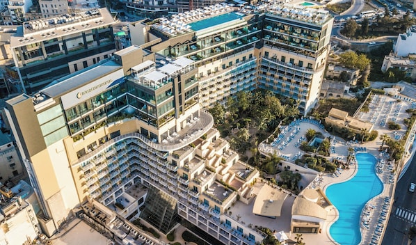 A multi-story hotel with a rooftop pool, outdoor seating, and a landscaped courtyard.