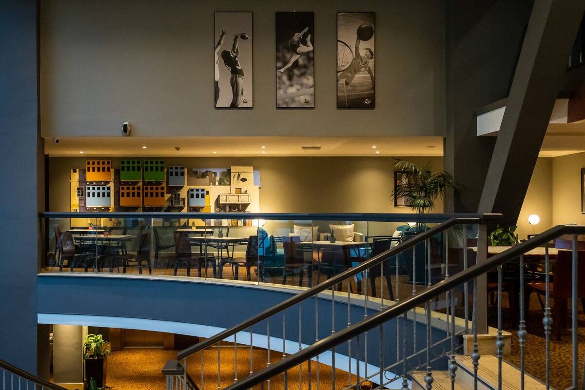 A multi-level hotel lobby with a staircase, seating areas, and artwork on the walls.
