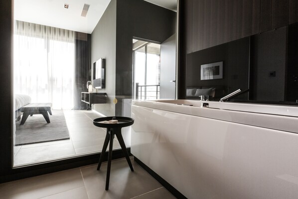 A modern hotel room with a large mirror, a white vanity, a small stool, and a view of the balcony. - InterContinental Malta by IHG (St. Julian's)