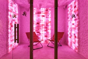A room with a pink-lit wall, two wooden chairs, and a wooden door. - InterContinental Malta by IHG (St. Julian's)