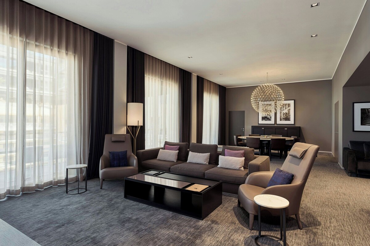 A modern hotel room with a sofa set, a coffee table, a side table, and a lamp.