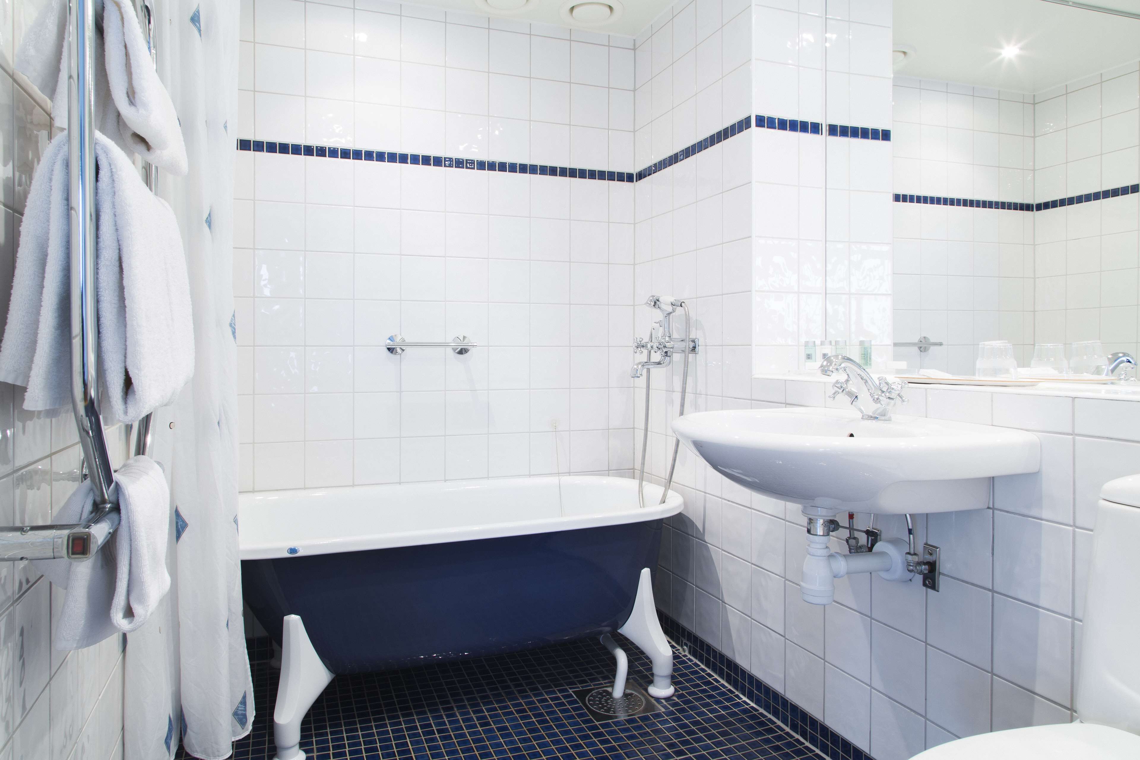 A bathroom with a bathtub, a sink, and a mirror.