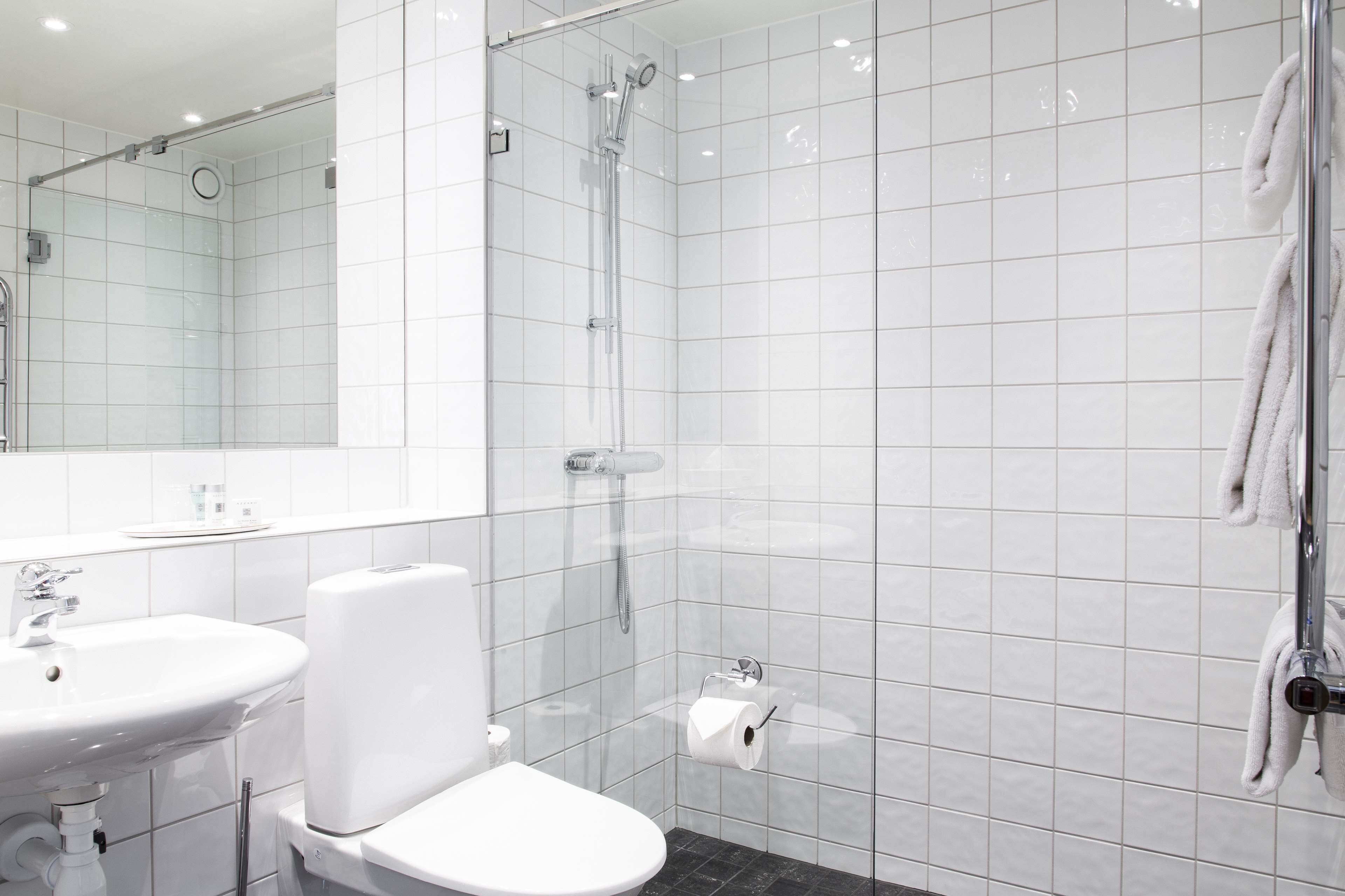 Un baño moderno con lavamanos blanco, inodoro y ducha con mampara de vidrio.