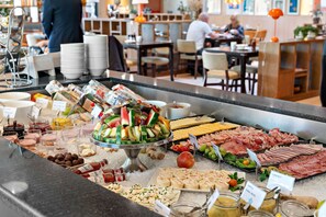 A buffet with various food items including fruits, cheeses, and meats.