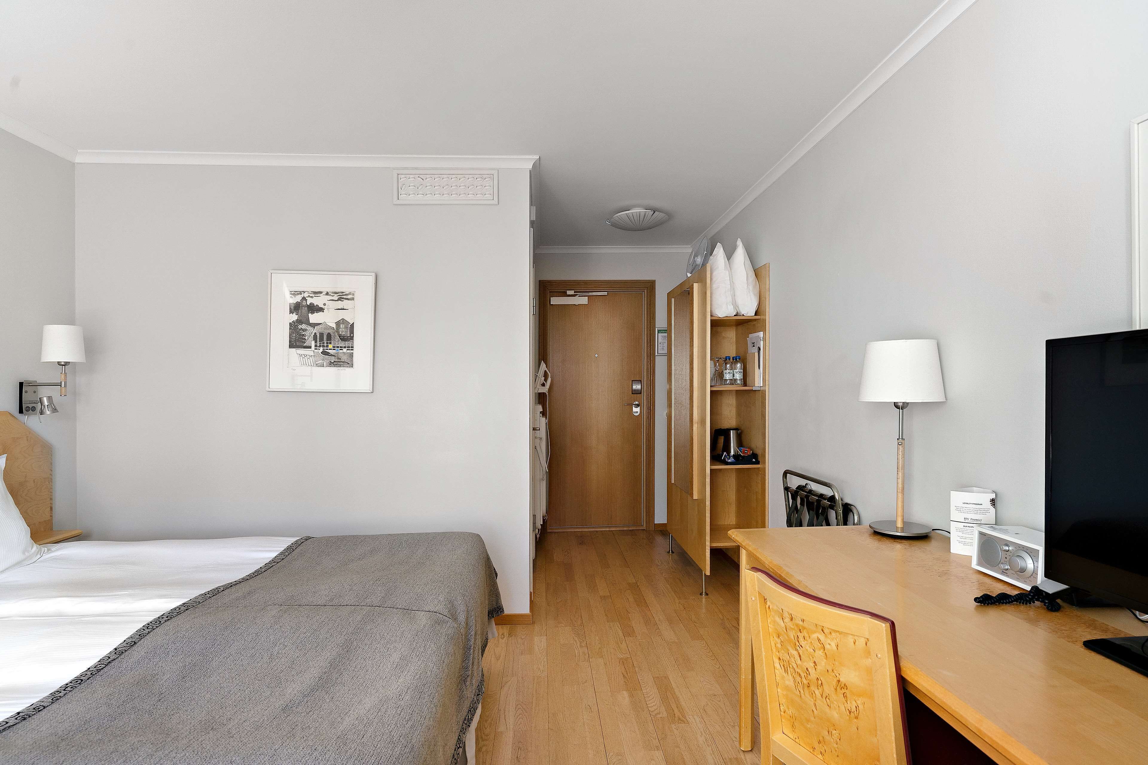 Une chambre d’hôtel comprenant un lit, un bureau, une chaise, une télévision et une armoire.
