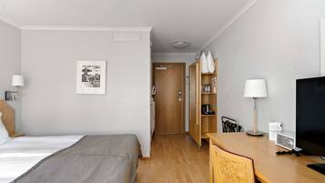 Une chambre d’hôtel comprenant un lit, un bureau, une chaise, une télévision et une armoire.