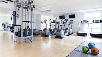 Un gimnasio con máquinas de cardio, equipo de pesas y pelotas de ejercicio.