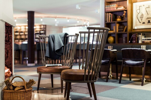 A cozy interior with wooden chairs, a fireplace, and a bookshelf.