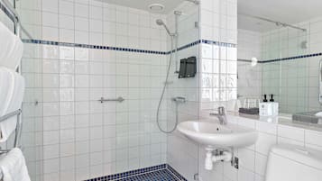 Ein modernes Badezimmer mit Duschkabine aus Glas, einem weißen Waschbecken und einem gefliesten Boden.
