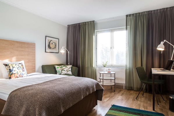 A hotel room with a bed, a desk with a laptop, a chair, a small table with a vase, and a window with curtains. - Landvetter Airport Hotel, BW Premier Collection (Harryda)