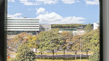 Vista de un estacionamiento con árboles y un edificio al fondo.