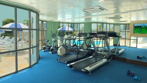 A gym with treadmills, ellipticals, and exercise equipment. There are windows with views of the outside, and a pool area with umbrellas. - Metropark Hotel Kowloon Hong Kong (Kowloon)