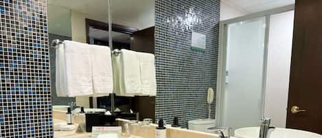 A bathroom with two sinks, a large mirror, and a towel rack with multiple towels.