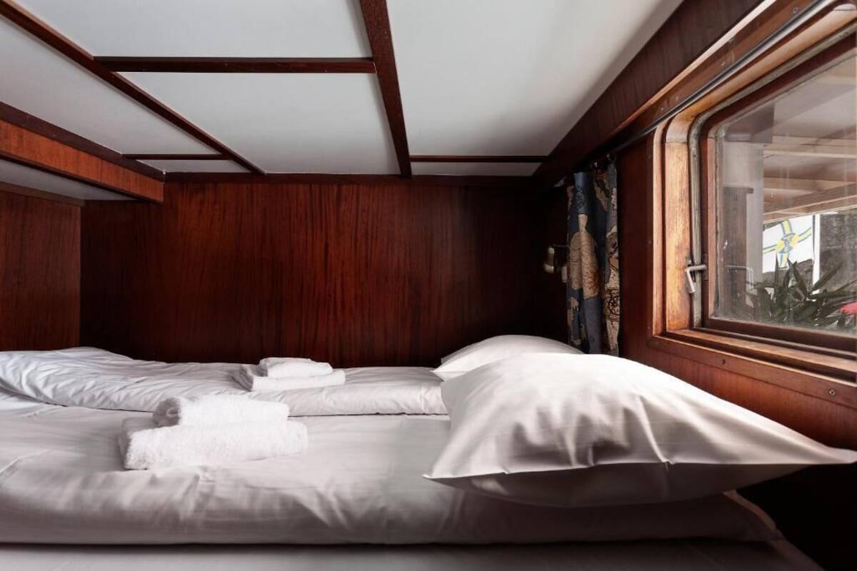 A cabin with two beds, wooden walls, and a window with a view.