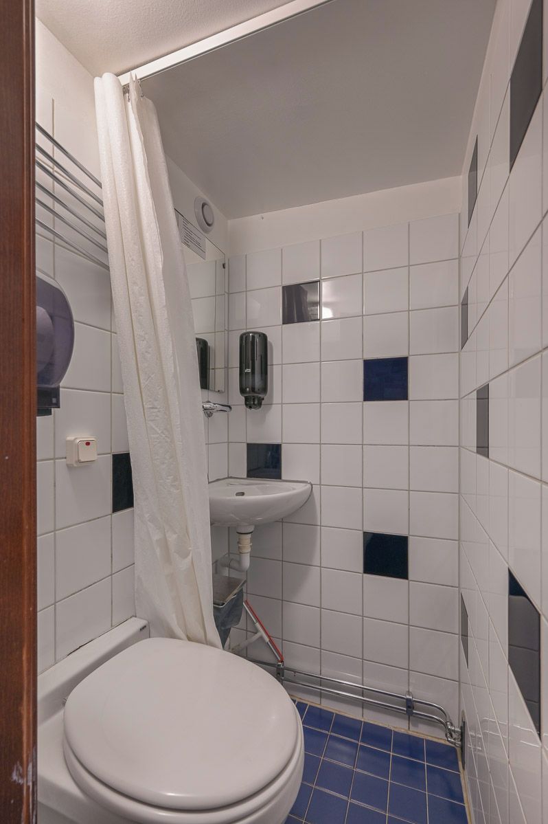 A small bathroom with a white toilet, a sink, and a shower curtain.