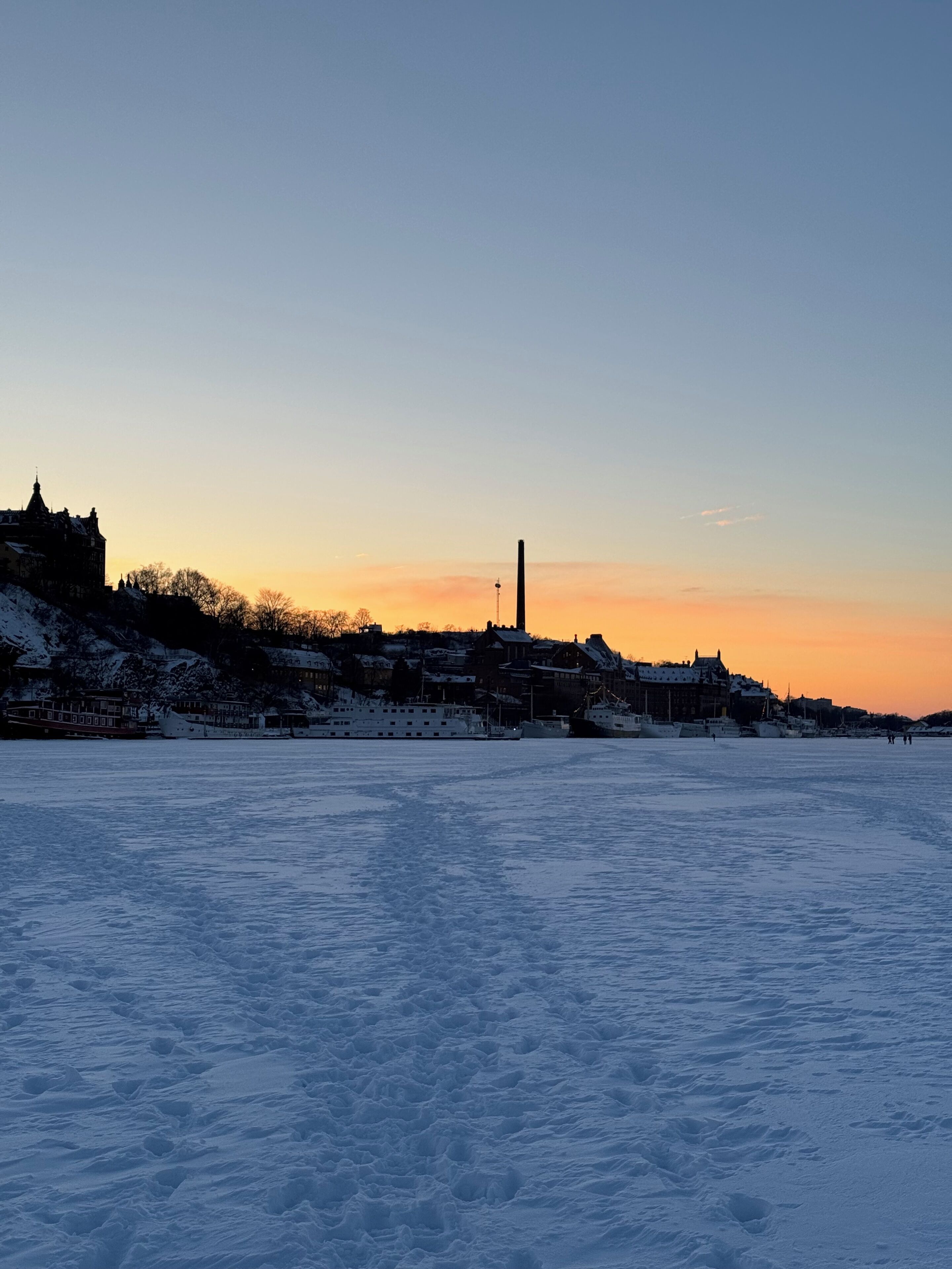 A snow-covered landscape with buildings and a tall chimney.