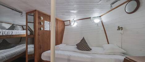 Una habitación tipo dormitorio con literas, un armario de madera, un espejo y una lámpara en el techo.