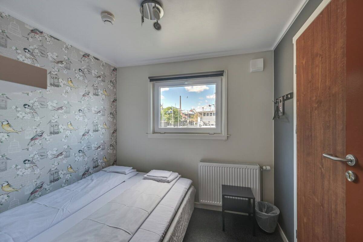 A small bedroom with a single bed, a radiator, a window with a view, and a door.