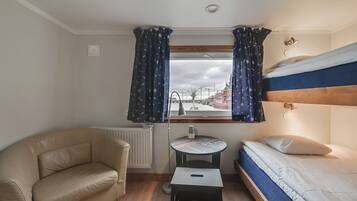 Une petite pièce, de taille modeste, comprenant un lit superposé, un canapé et une petite table.