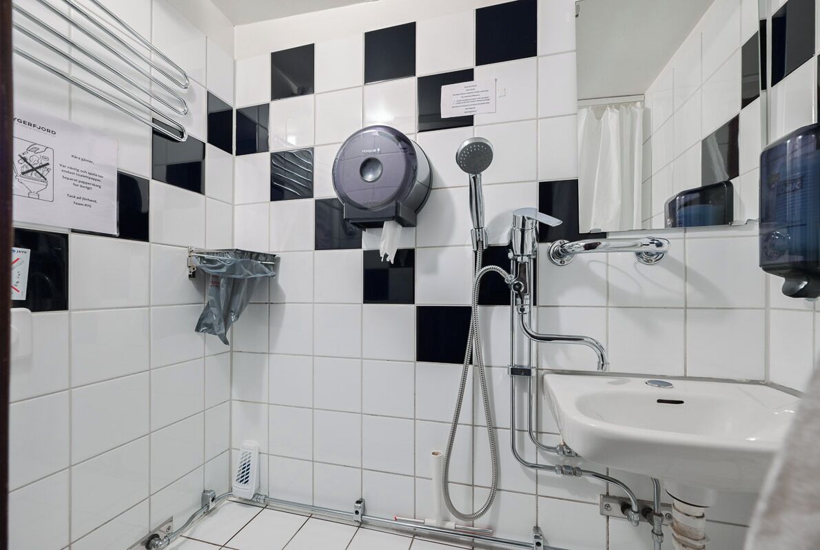 Ein Badezimmer mit Dusche, Waschbecken und Handtuchspender.