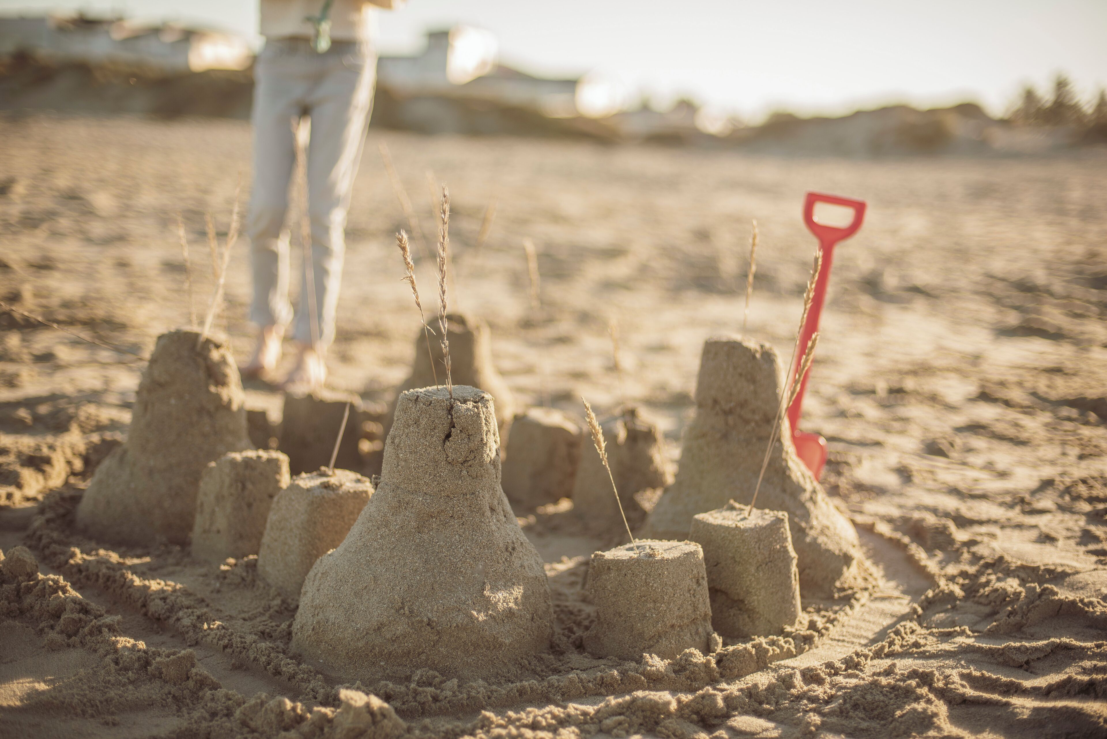 Sand structures on a beach with a red shovel.