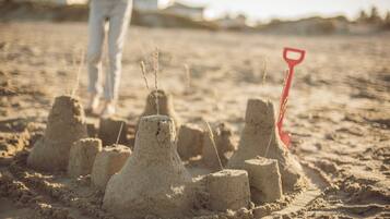 Sand structures on a beach with a red shovel.