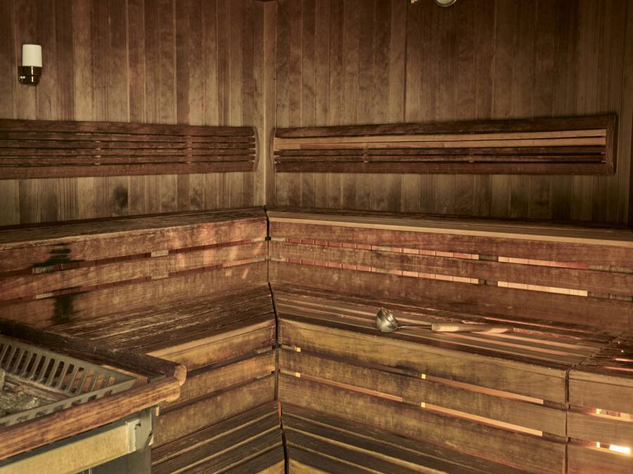 Una sauna con bancos de madera y una rejilla metálica.