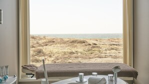 A room with a large window overlooking a beach. - Sola Strand Hotel (Sola)