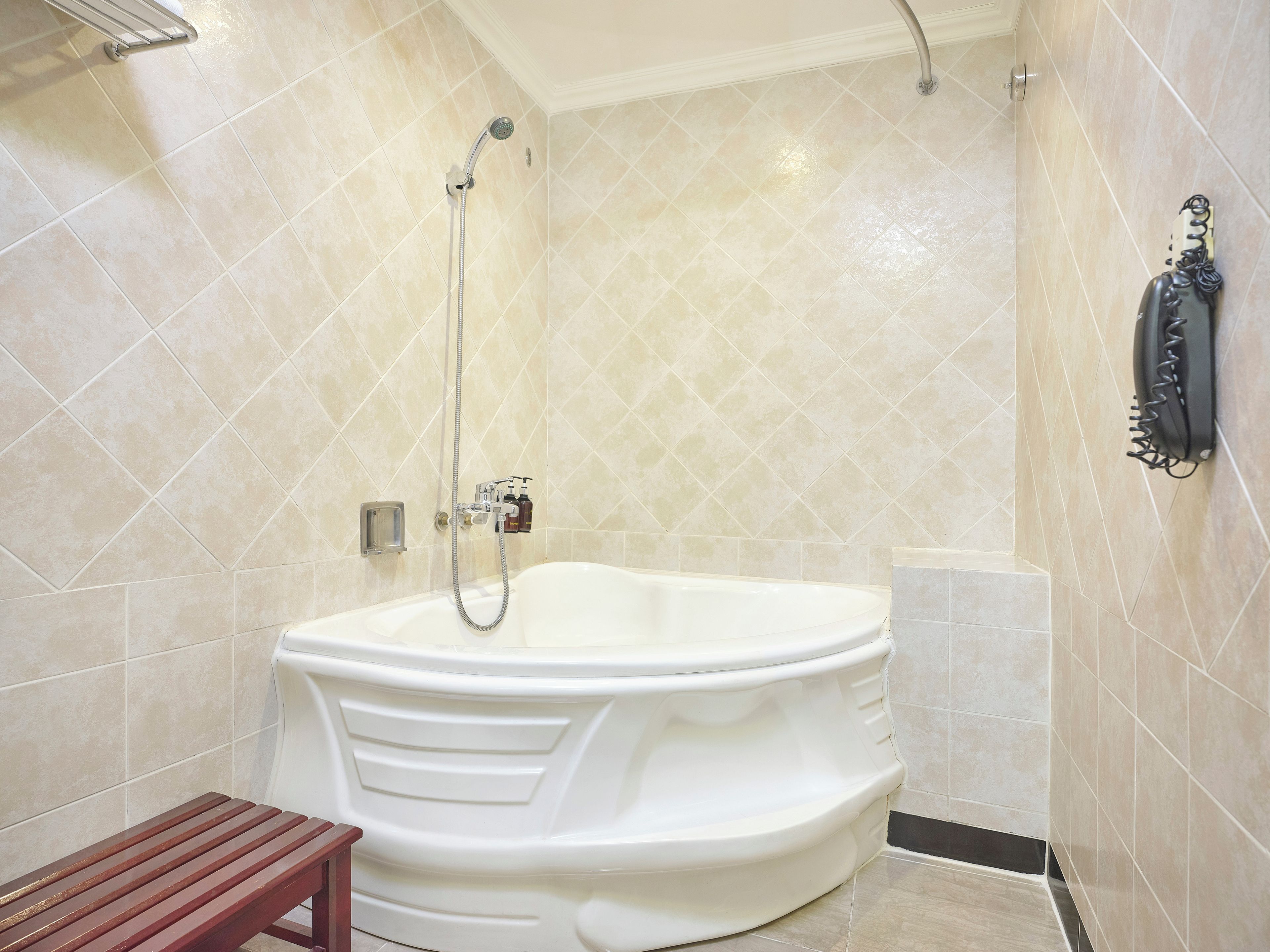 A bathroom with a freestanding bathtub, a showerhead, and a towel rack.