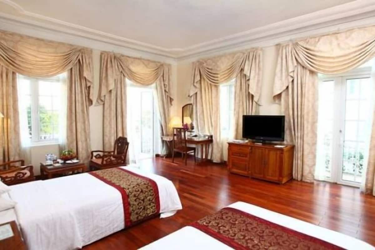 Une chambre d’hôtel avec deux lits, une télévision, un bureau et une chaise.