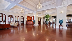 A spacious lobby with a polished floor, a reception desk, and a chandelier.