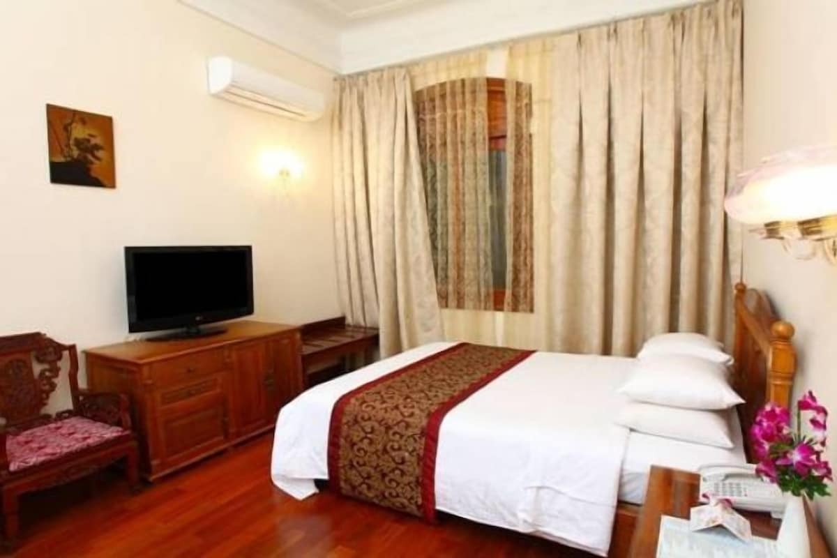 A hotel room with a bed, a television, a desk, and a chair.