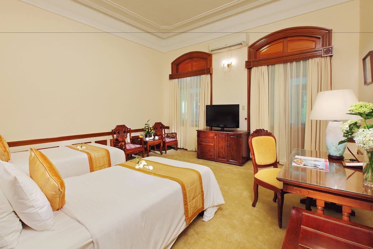 Une chambre d’hôtel avec deux lits, une télévision, un bureau et une chaise.