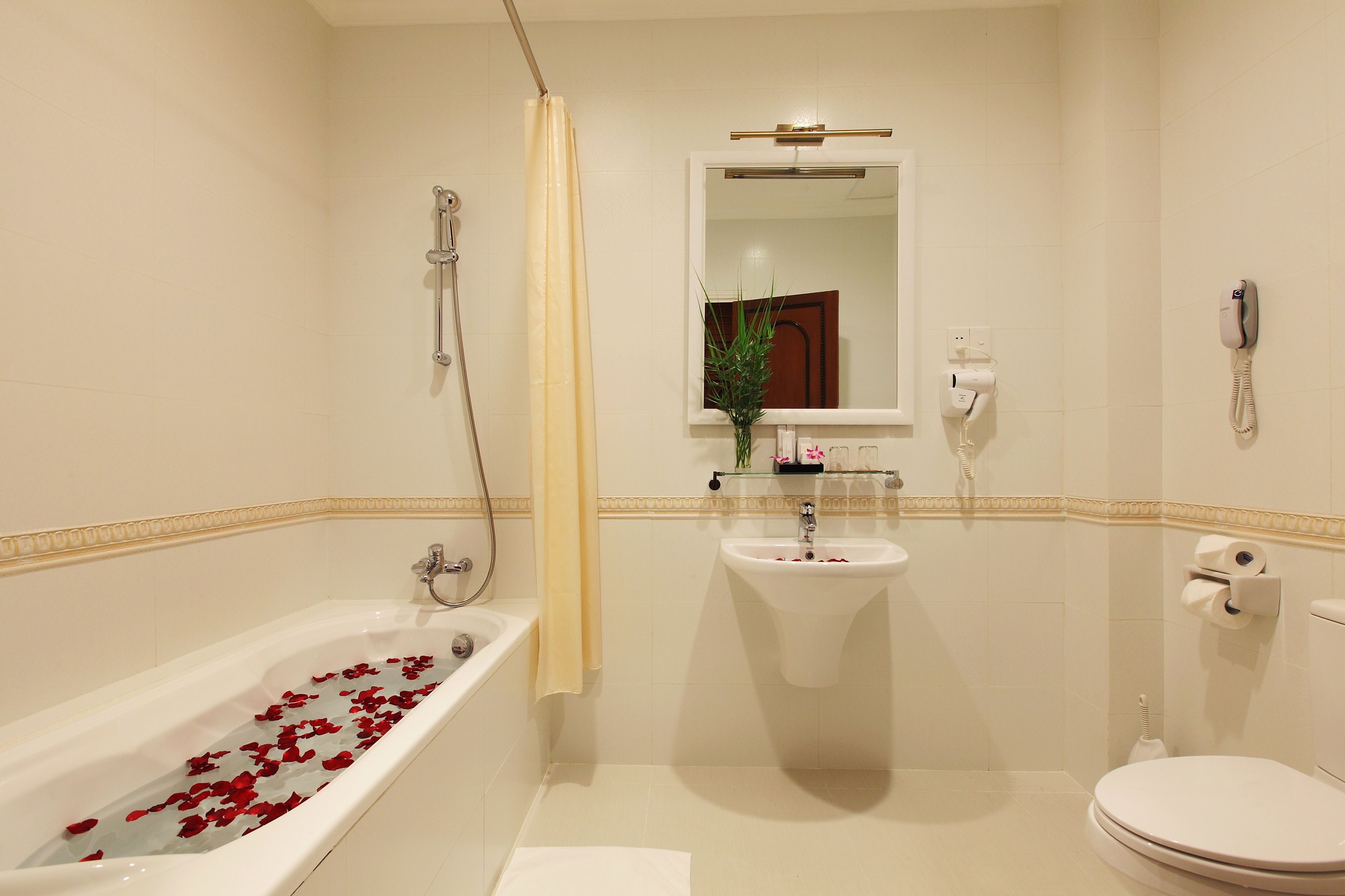 A bathroom with a bathtub filled with rose petals, a sink, a toilet, and a shower.