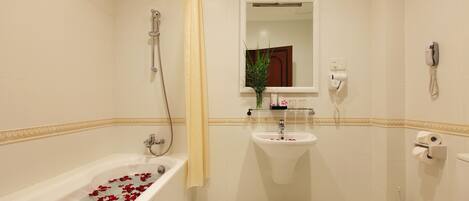 A bathroom with a bathtub filled with rose petals, a sink, a toilet, and a shower.