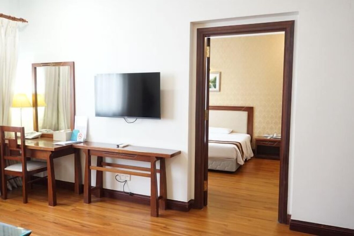 Een hotelkamer met een houten bureau, een televisie, een bed en een spiegel.