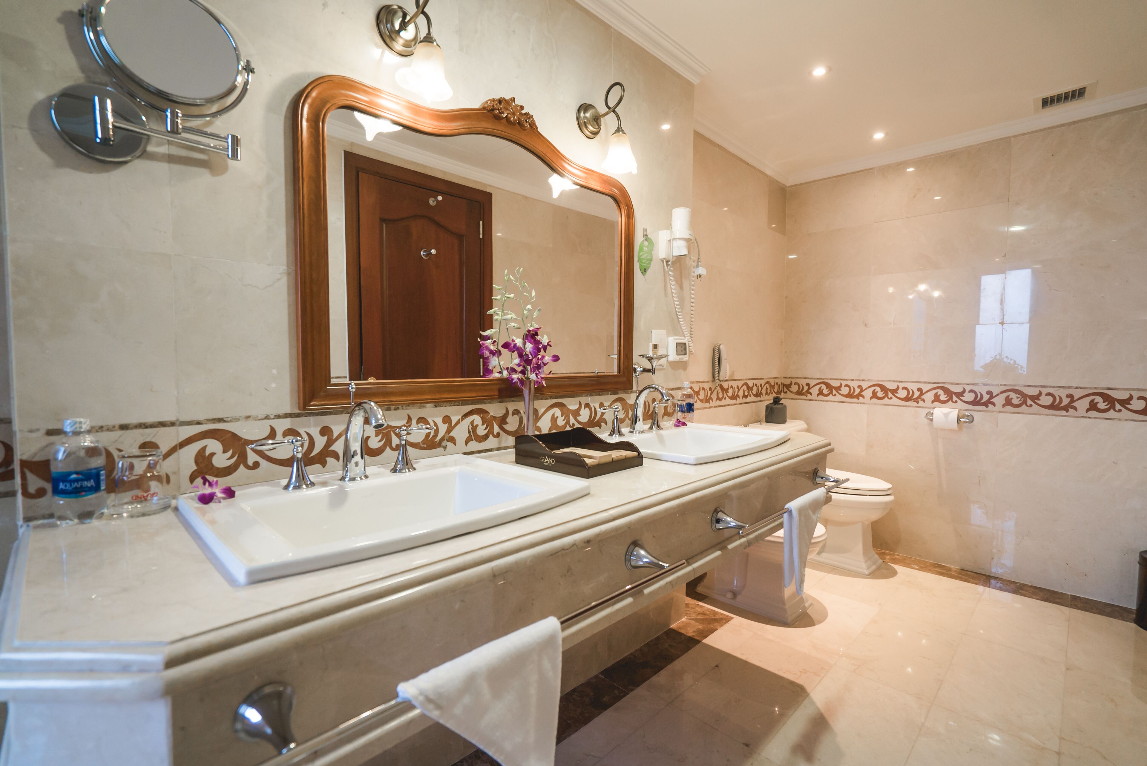 A bathroom with two sinks, a toilet, a large mirror, and a towel rack.