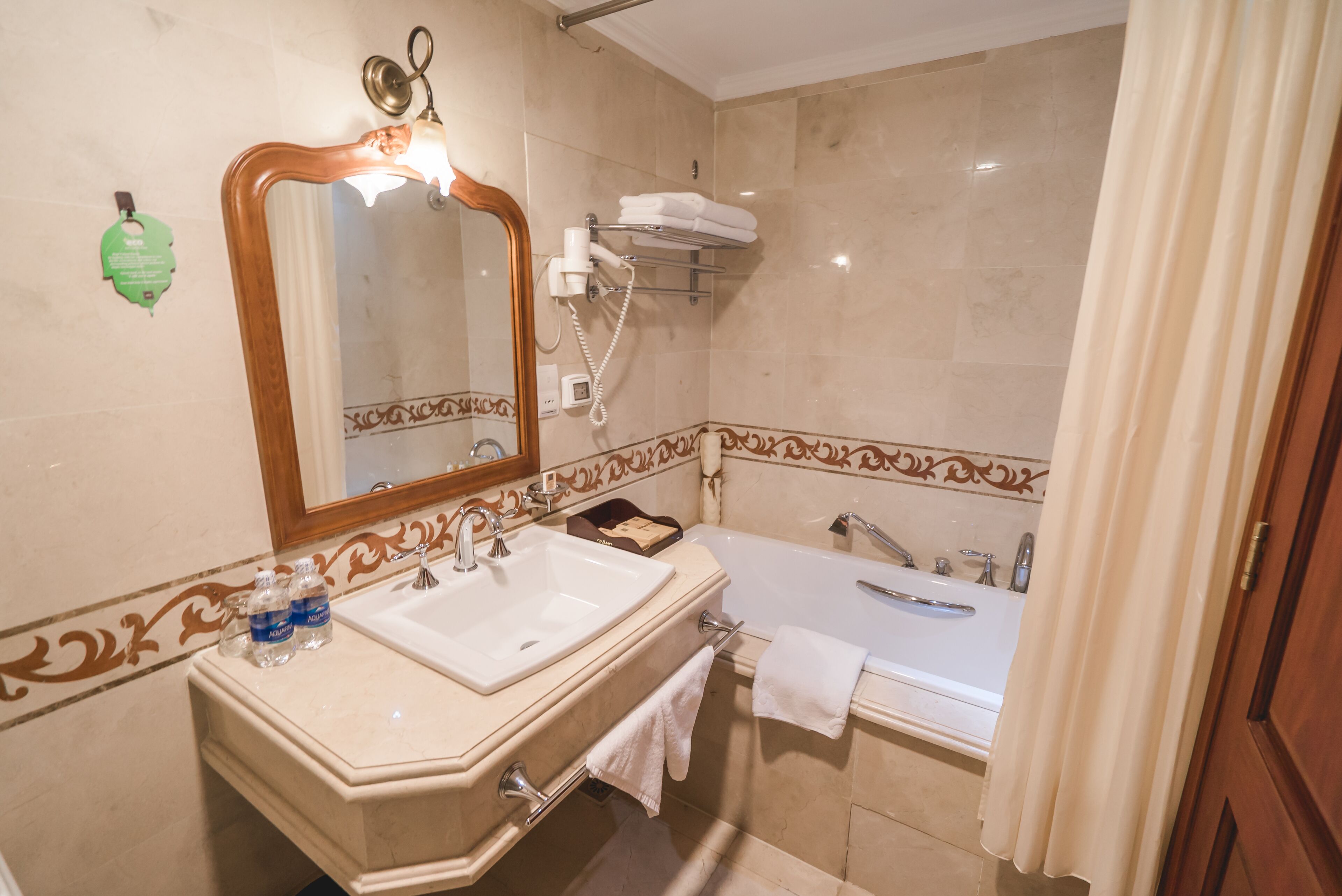 A bathroom with a sink, mirror, towel rack, and bathtub.