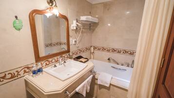 A bathroom with a sink, mirror, towel rack, and bathtub.