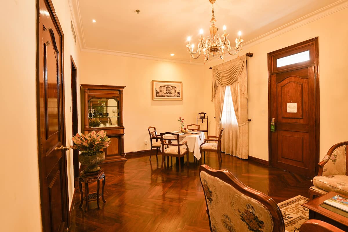 A dining area with a chandelier, wooden furniture, and a table set for four.
