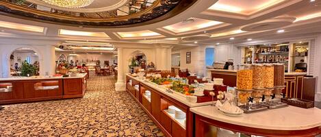 A spacious hotel lobby with a central bar area, decorative ceiling, and patterned carpet.