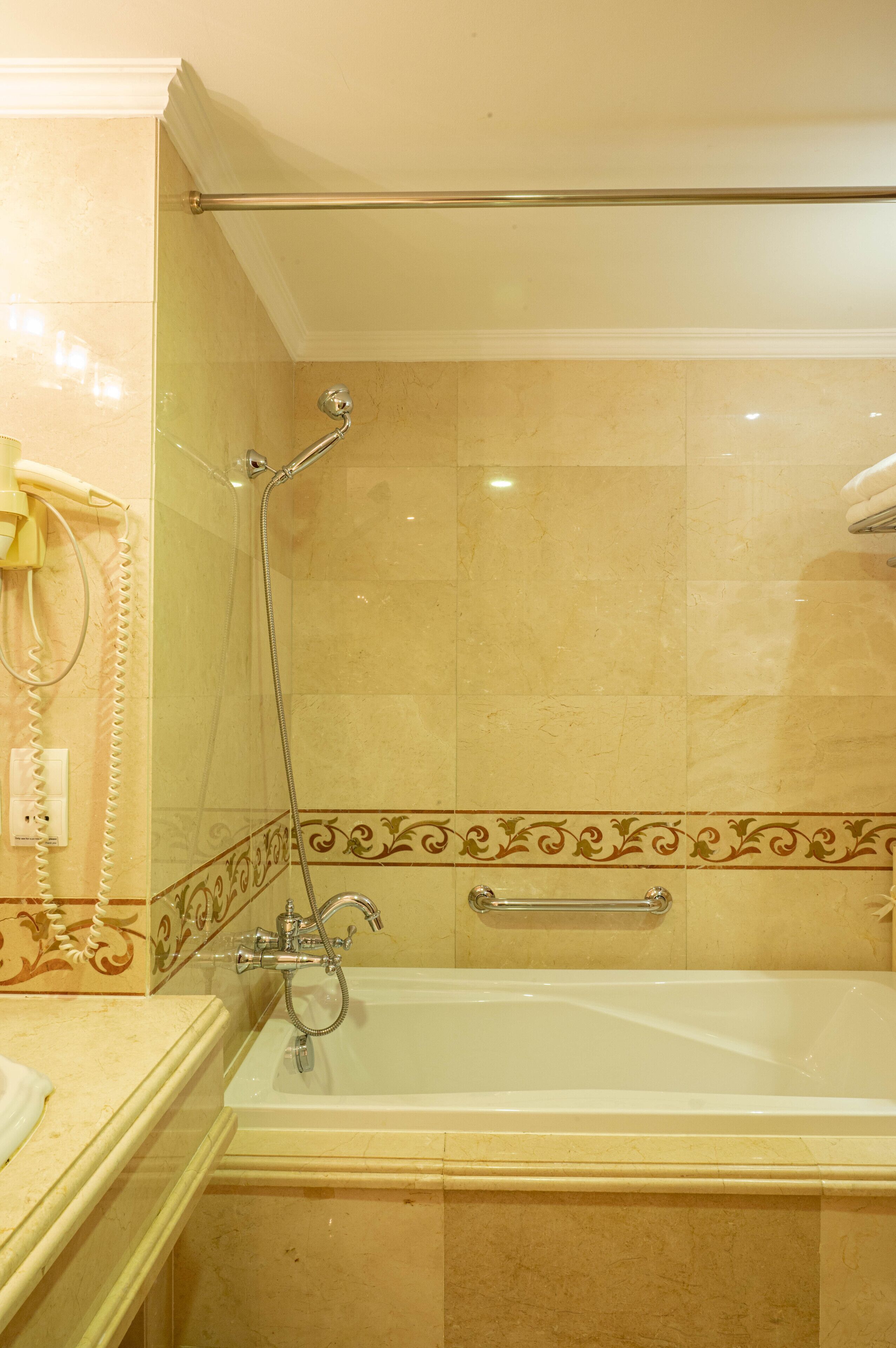 A bathroom with a bathtub, a shower, and a telephone.