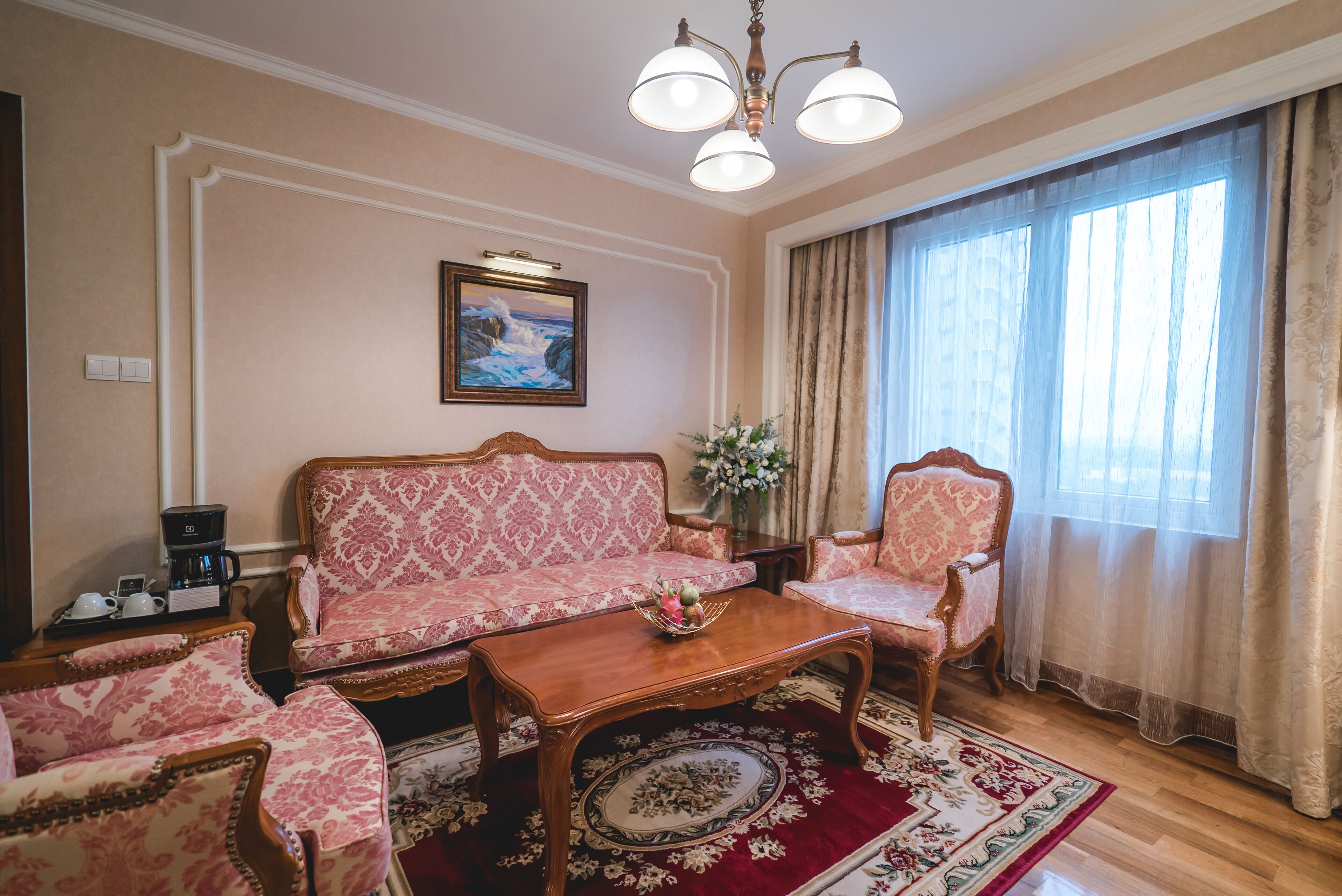 A room with a patterned sofa, a wooden coffee table, and a floral rug.