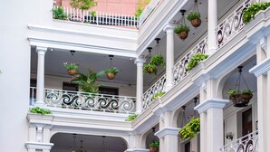 A multi-story building with a swimming pool, outdoor seating, and hanging planters. - Hotel Grand Saigon (Ho Chi Minh City)