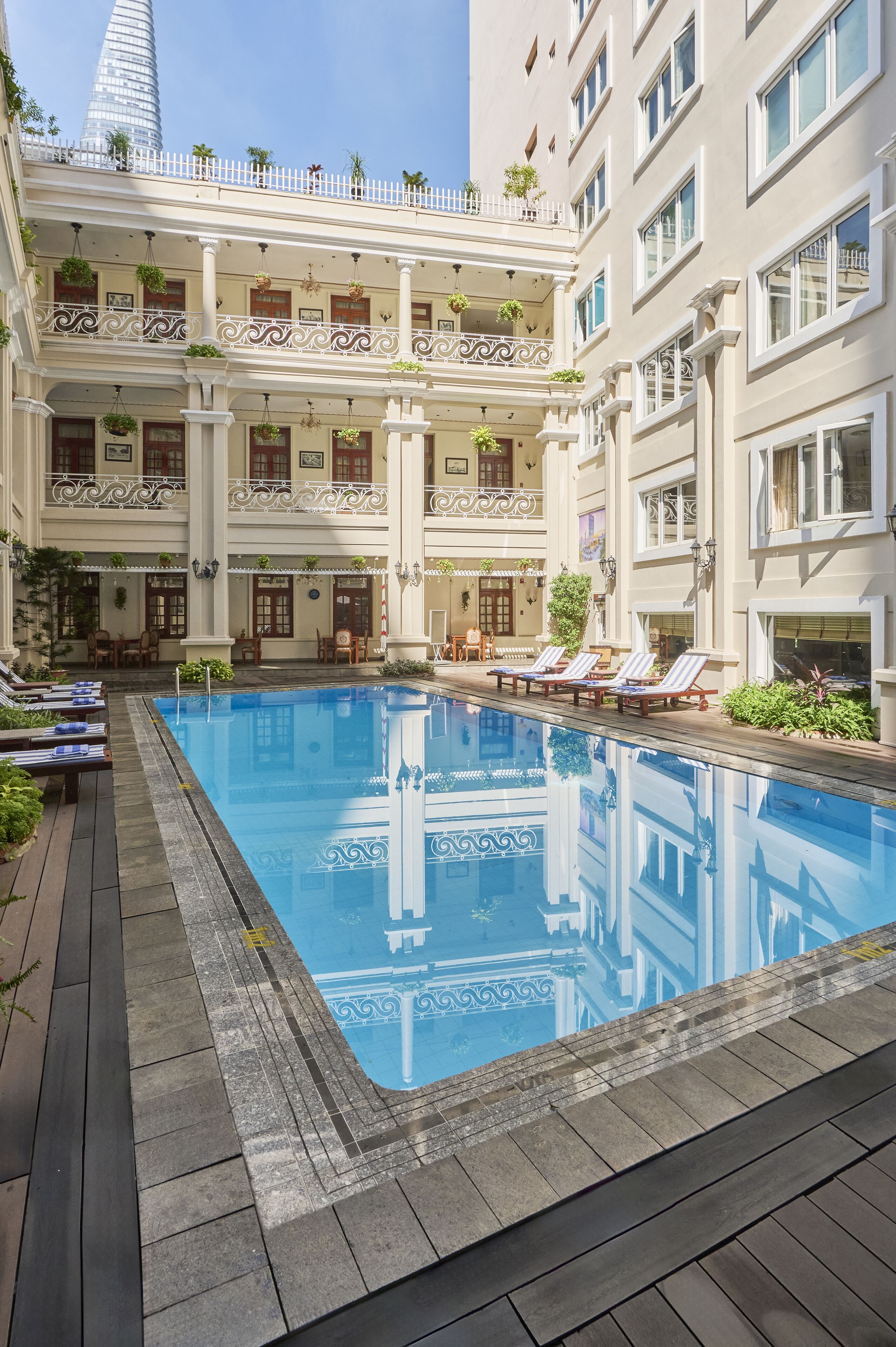 Un área de piscina con piscina azul cristalina, terraza de madera y sillones de descanso.