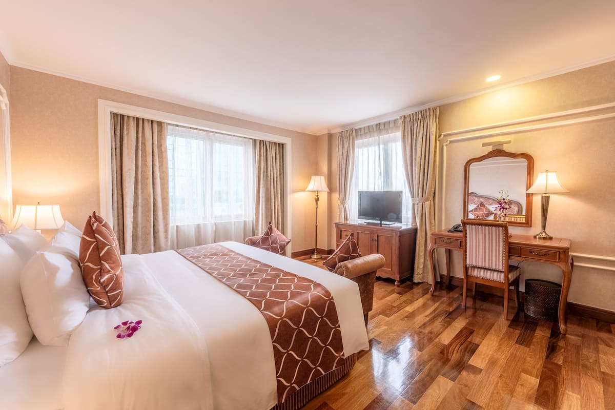 A hotel room with a large bed, a desk, a television, and a mirror.